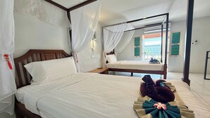 Habitación de hotel con dos camas, una con dosel y la otra sin. Hay una toalla y un arreglo floral sobre la cama.