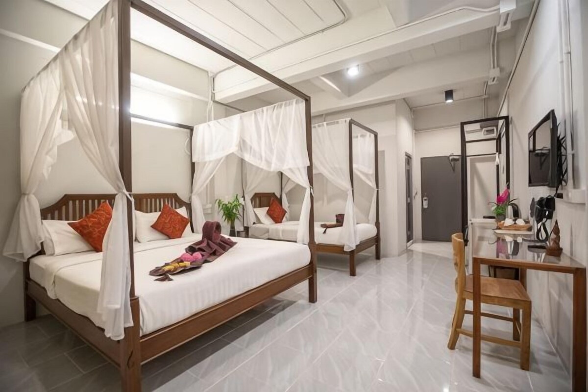 A four-poster bed with a canopy, a wooden desk with a chair, and a mirror on the wall.