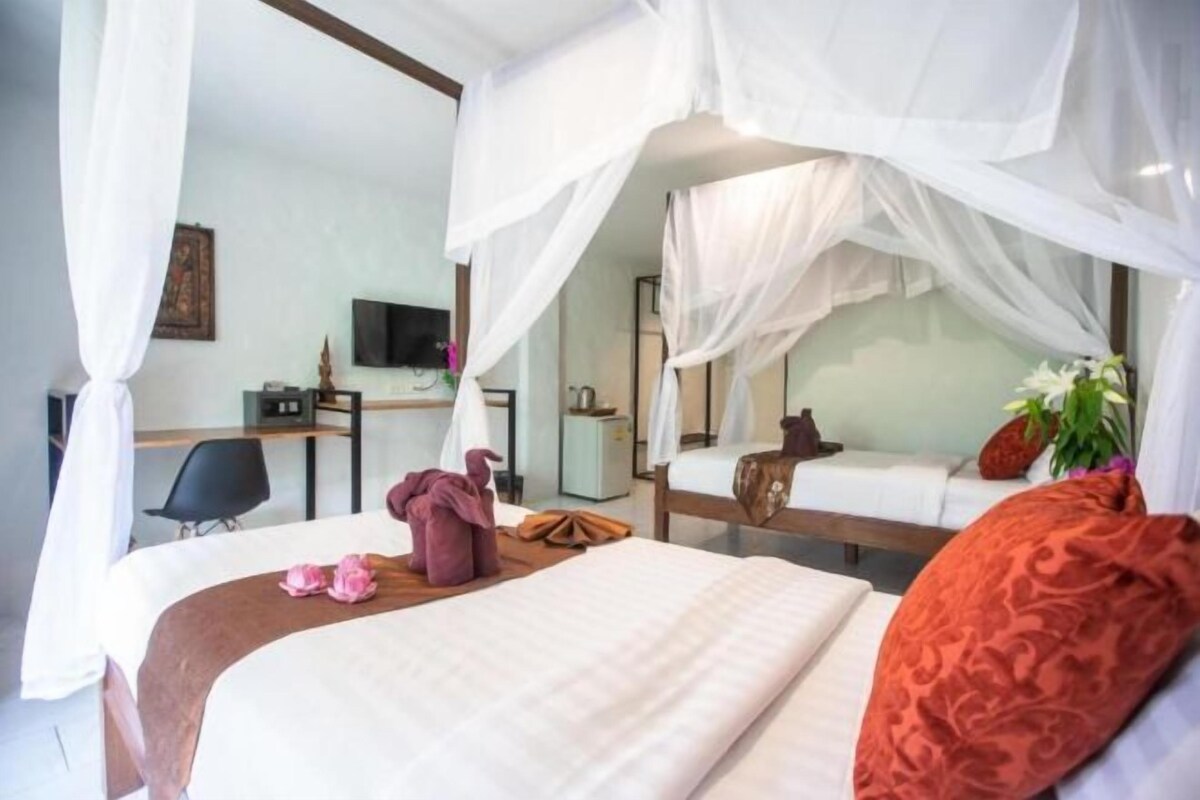 A hotel room with a bed, a desk, a chair, and a television.