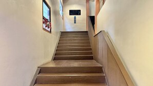 Una escalera de madera con barandilla que lleva a una puerta con el número 2.