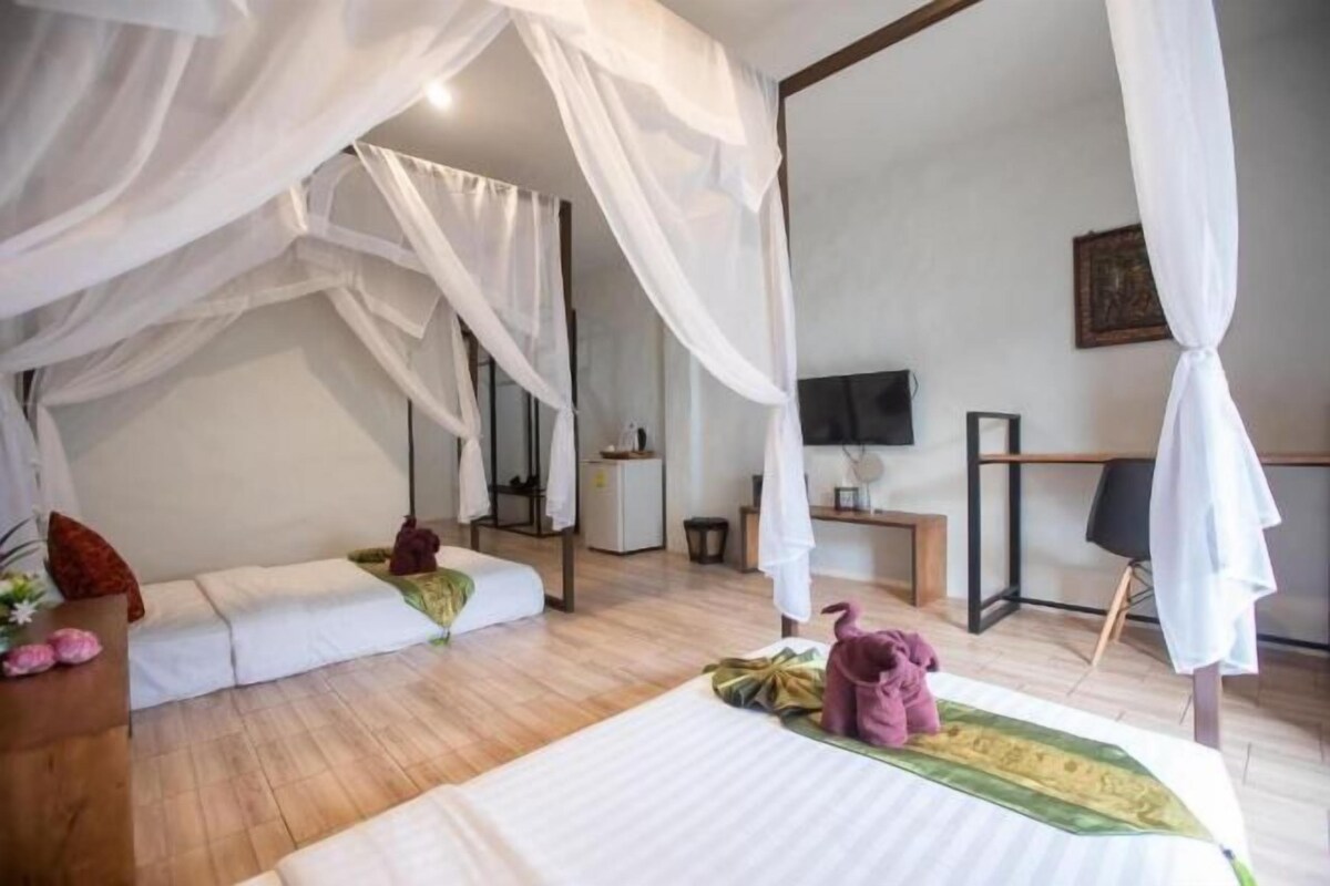 A bedroom with a canopy bed, a television, and a desk with a chair.