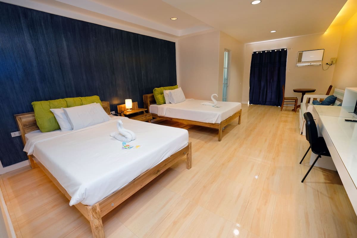 A hotel room with two wooden beds, a desk, and a chair.