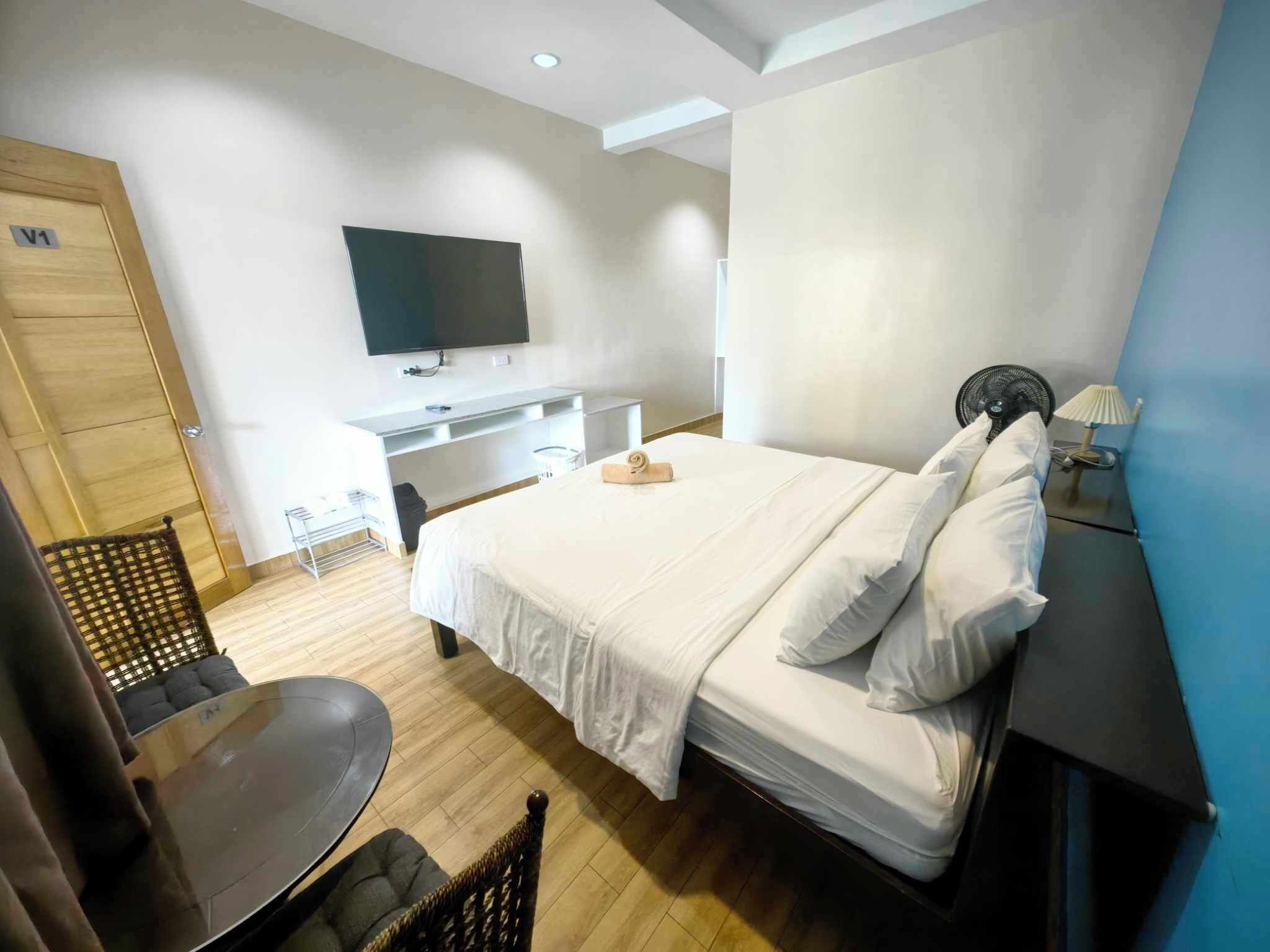 Una habitación de hotel moderna con una cama, un televisor, un escritorio y una silla.