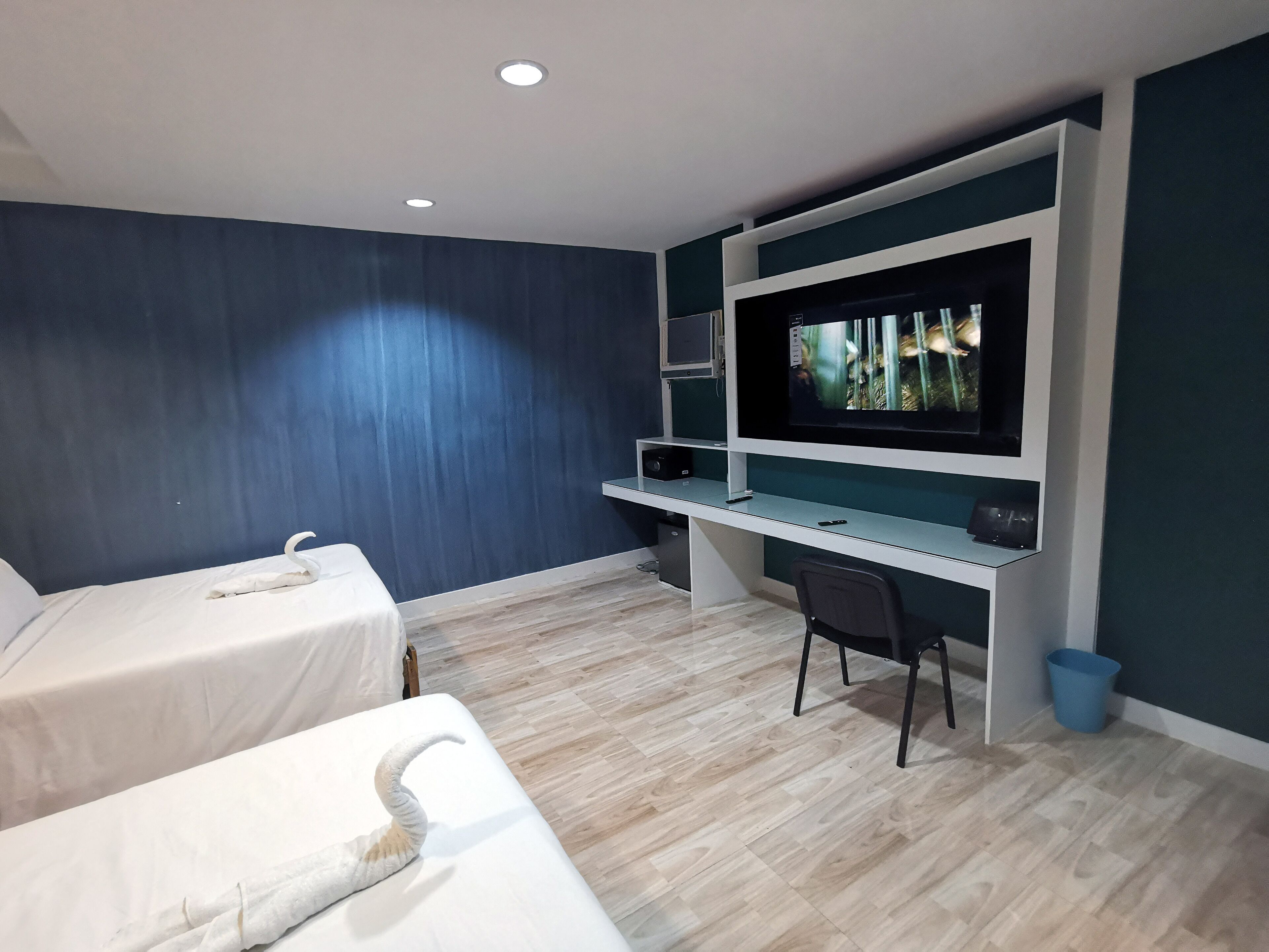 Una habitación de hotel con dos camas, un escritorio con televisor y una silla.