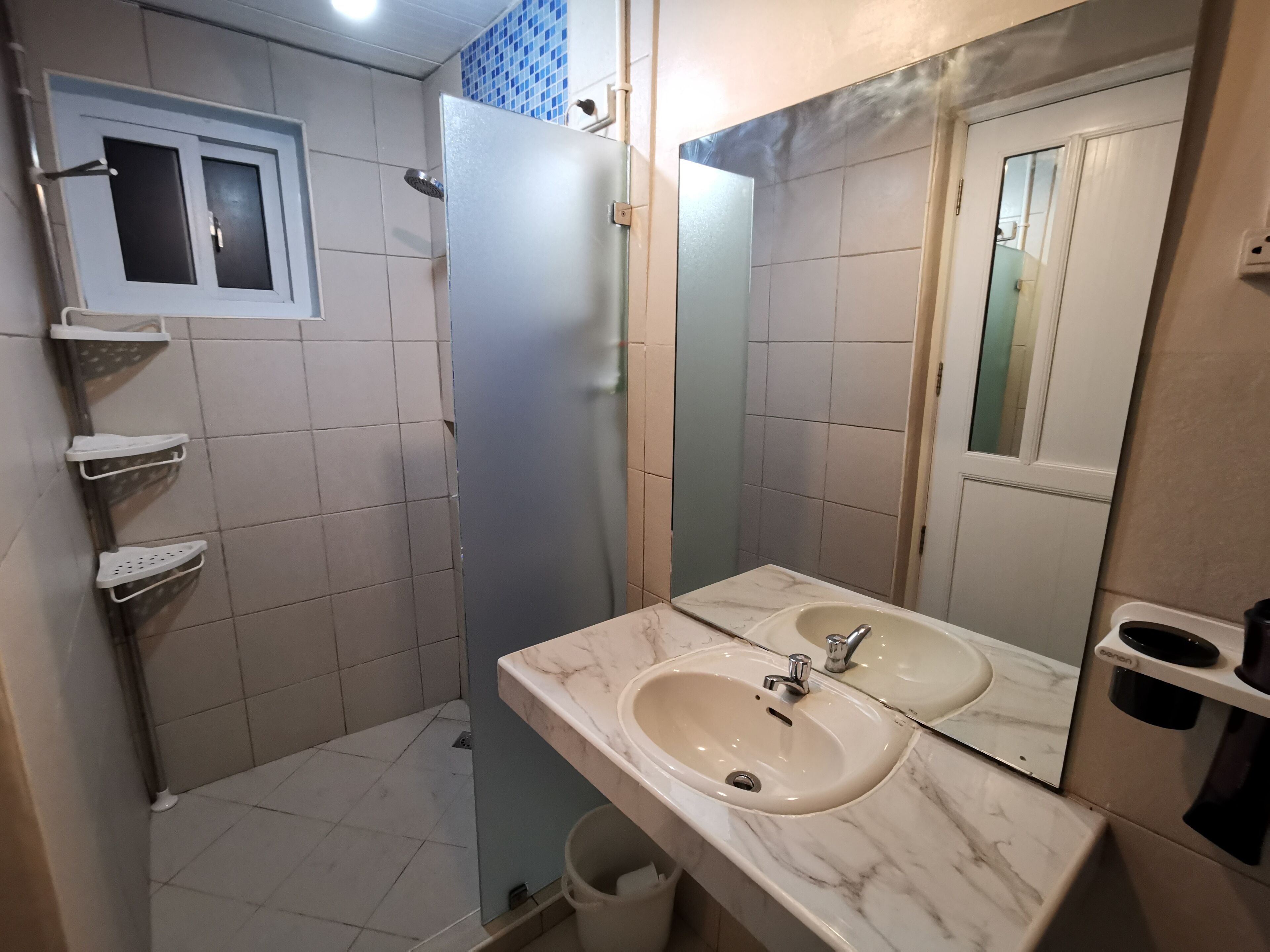 Un bagno con due lavandini, uno specchio e una cabina doccia.