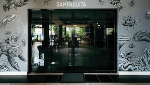 La entrada de un restaurante llamado 'Sampaguita' con un mural de temática marina en las paredes.