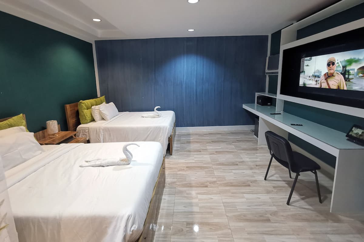 A hotel room with two beds, a desk with a TV, and a chair.
