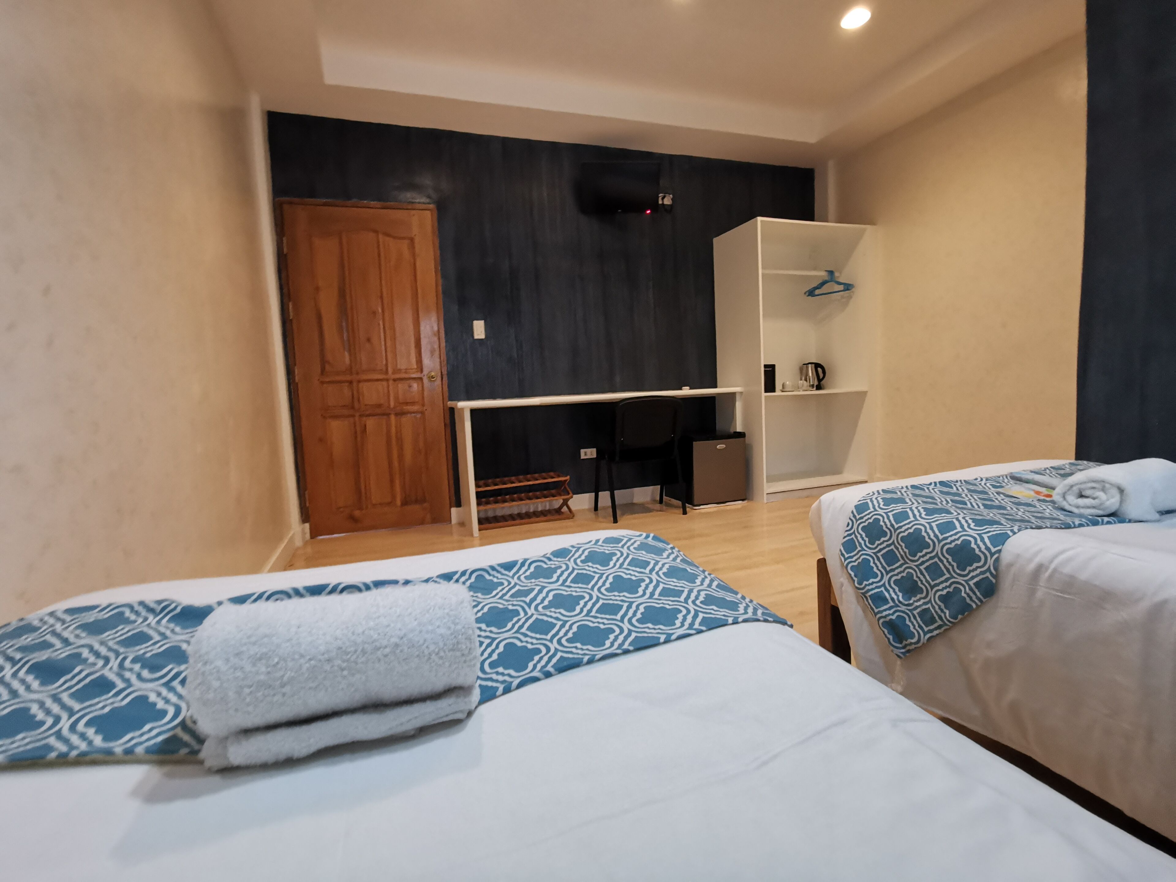 Ein Hotelzimmer mit zwei Betten, einem Schreibtisch, einem Kleiderschrank und einer Tür.
