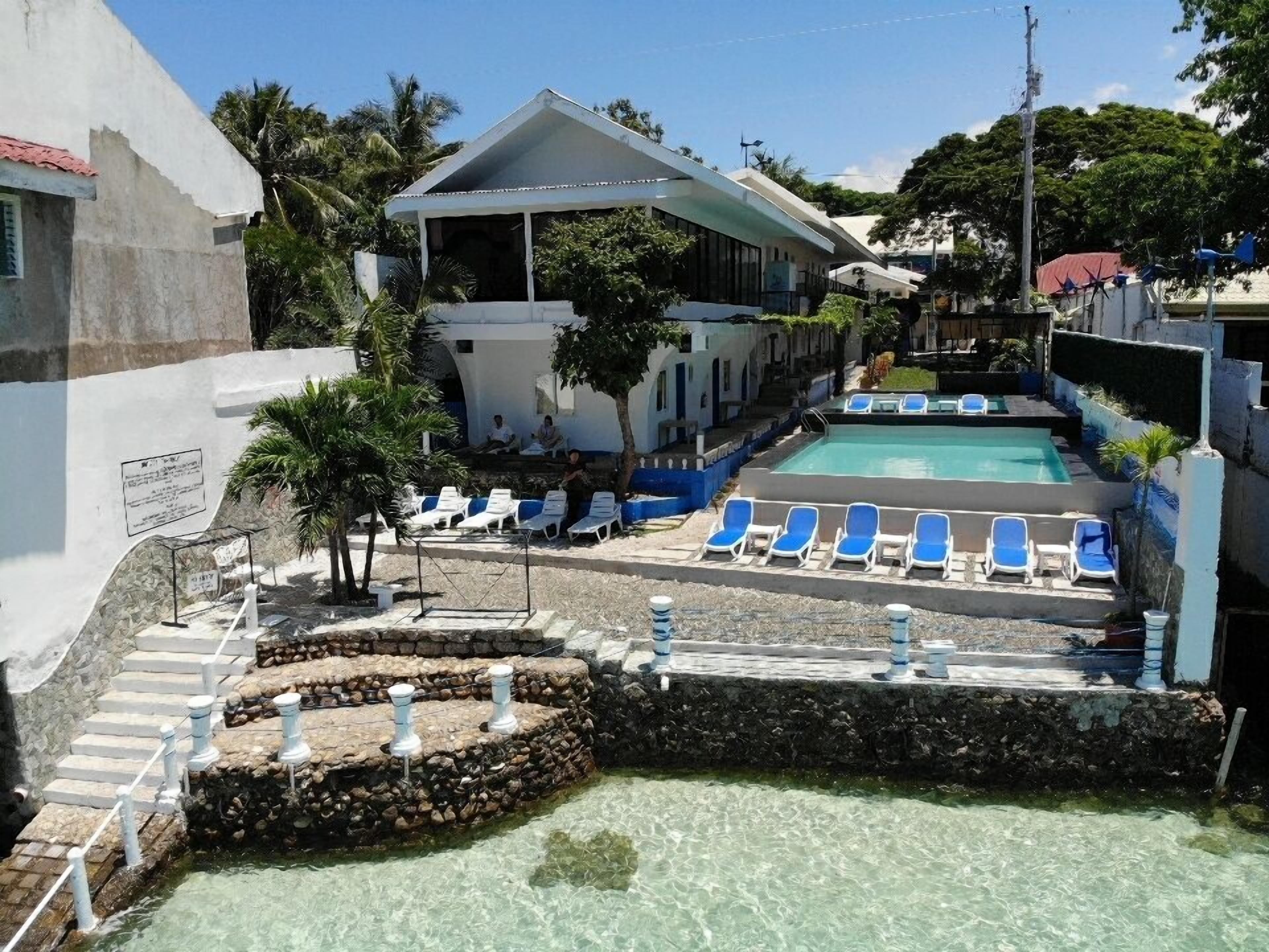A pool area with clear water, surrounded by lounge chairs and a stone wall.