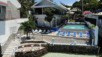 A pool area with clear water, surrounded by lounge chairs and a stone wall.