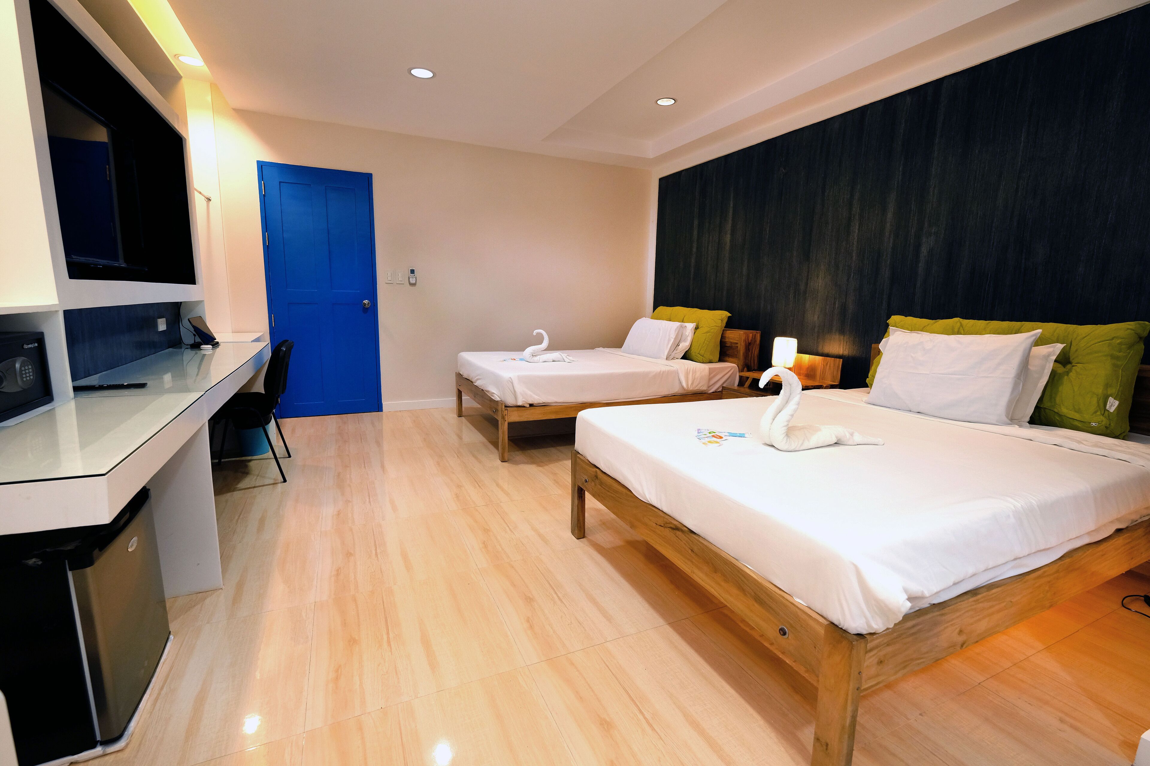 Habitación de hotel con dos camas, un escritorio, una silla y un televisor.