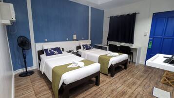 Habitación de hotel con dos camas, un escritorio, una silla, un ventilador y una puerta azul.