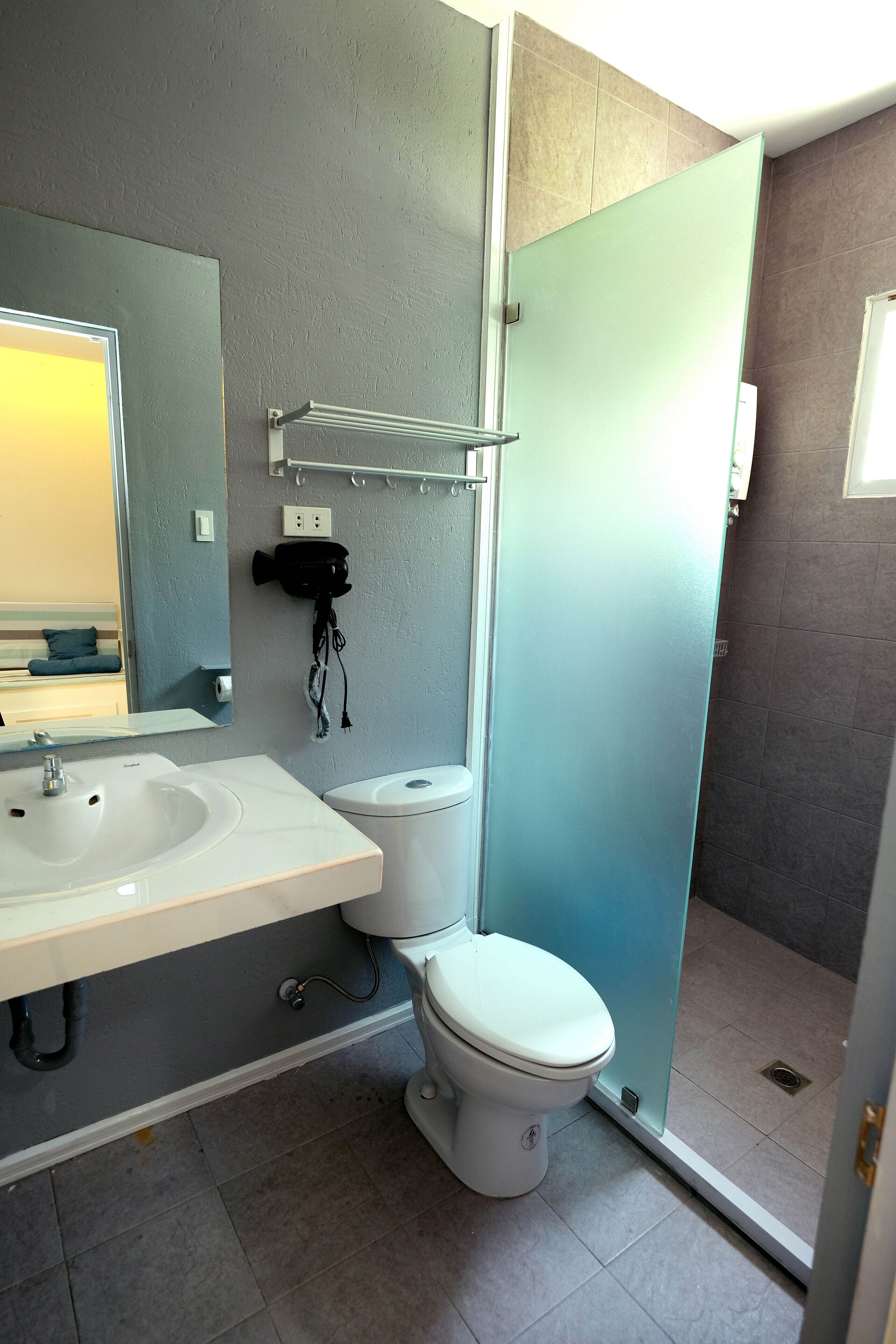 A modern bathroom with a white sink, a toilet, and a glass shower enclosure.