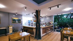 Un restaurante con mesas y sillas de madera, una barra con menú y vistas a zonas verdes.