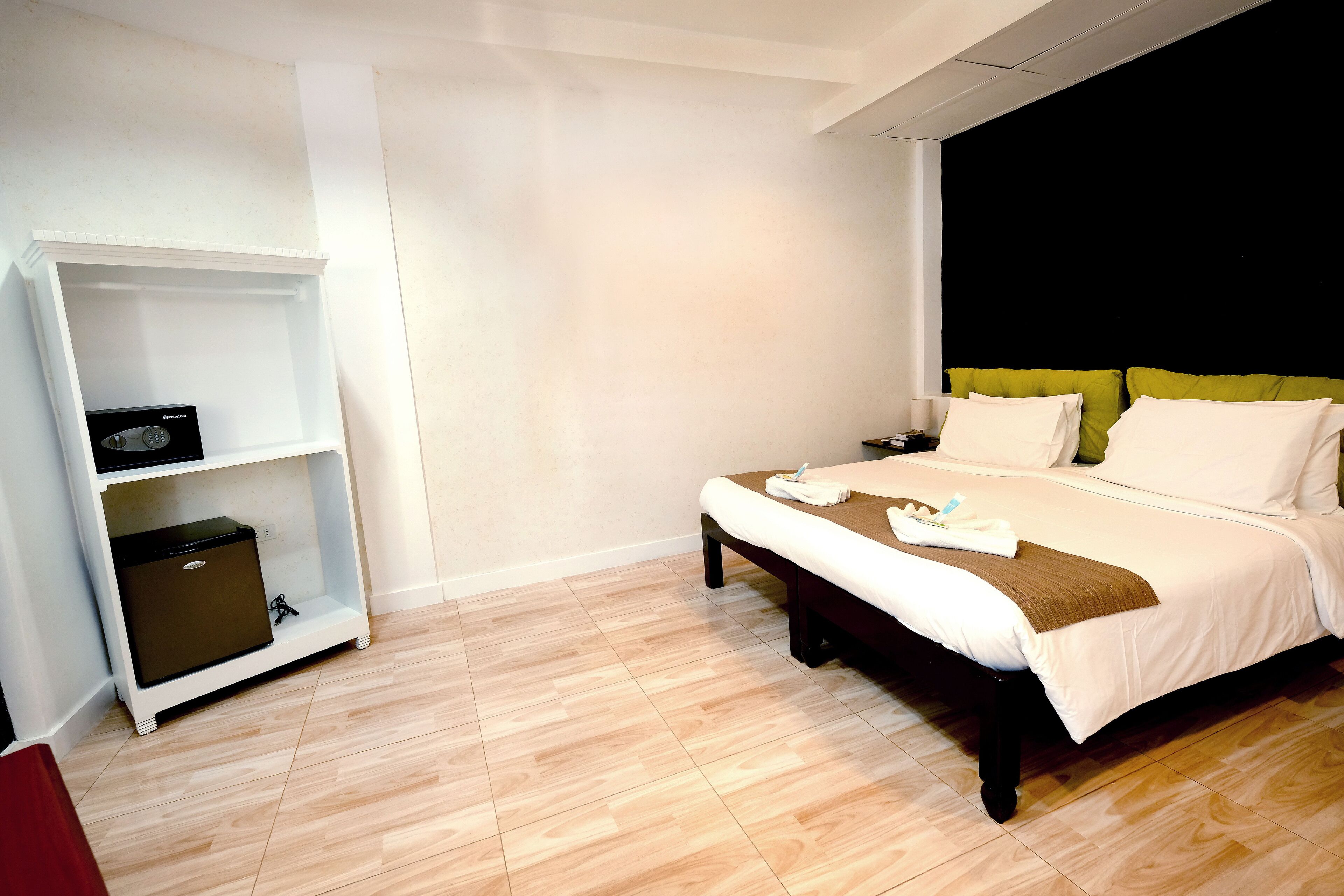 A hotel room with a bed, a bedside table, a nightstand, a wardrobe, and a small cabinet.