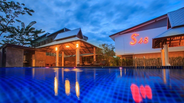 Un hotel con piscina, un espacio exterior cubierto y un cartel destacado que dice 'S48'.