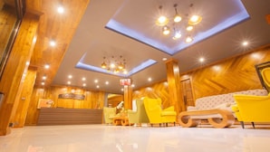 Un vestíbulo de hotel con paneles de madera, un mostrador de recepción, un sofá y varias sillas.