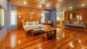 Una habitación amplia con una cama grande, un banco de madera y un sofá. Hay un tragaluz sobre la cama y una ventana a la izquierda.