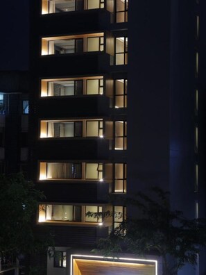 A modern multi-story building with illuminated windows and balconies at night.