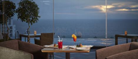 A dining area with a table set for two, overlooking a body of water.
