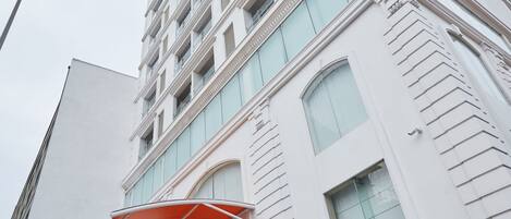 A modern hotel with a prominent entrance, large windows, and a red canopy.