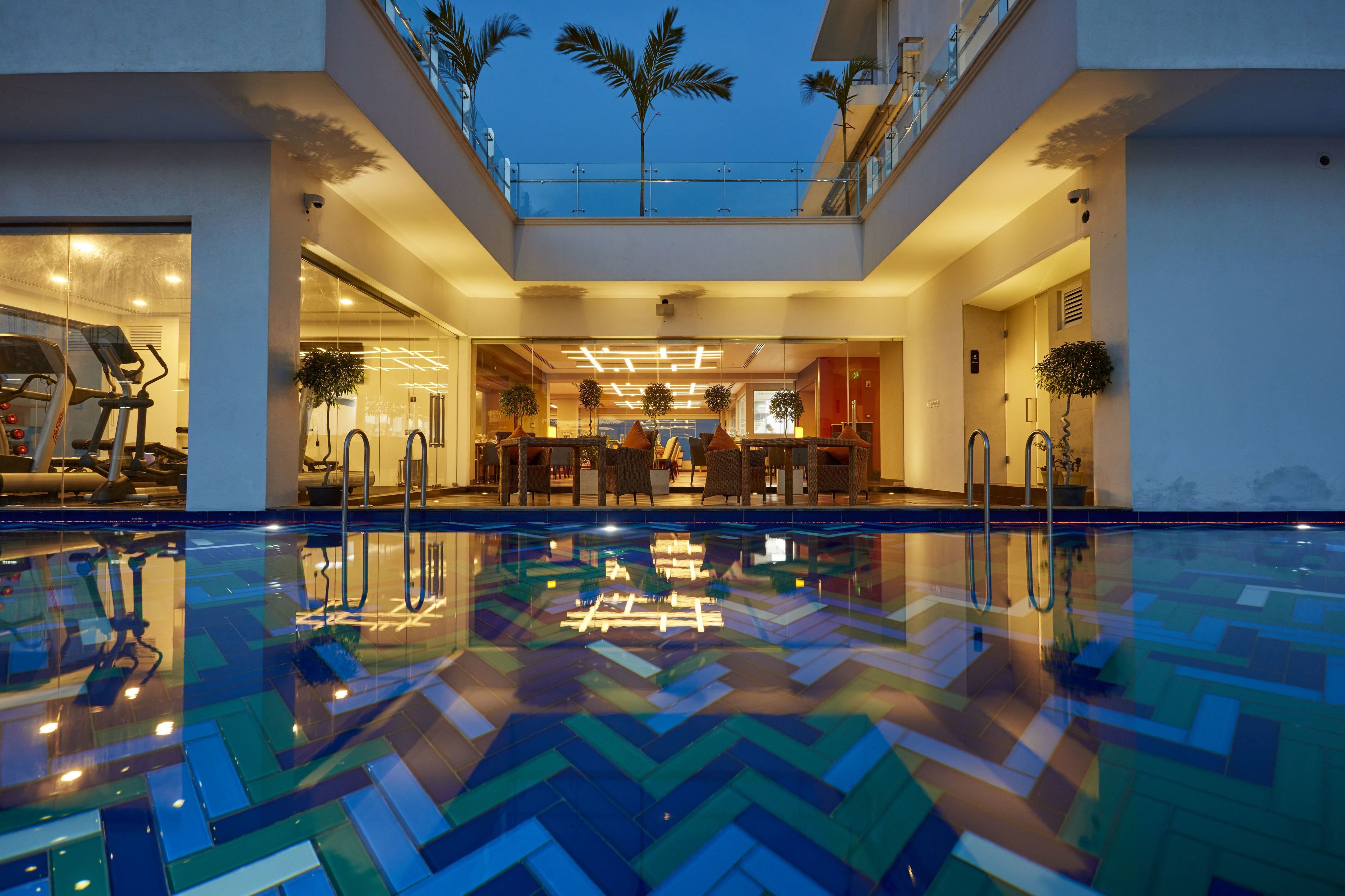 En modern hotellinredning med en swimmingpool, träningsutrustning och en väl upplyst innergård.