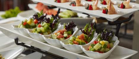 Un bufé con diversos platos, incluyendo ensaladas y aperitivos de camarones.
