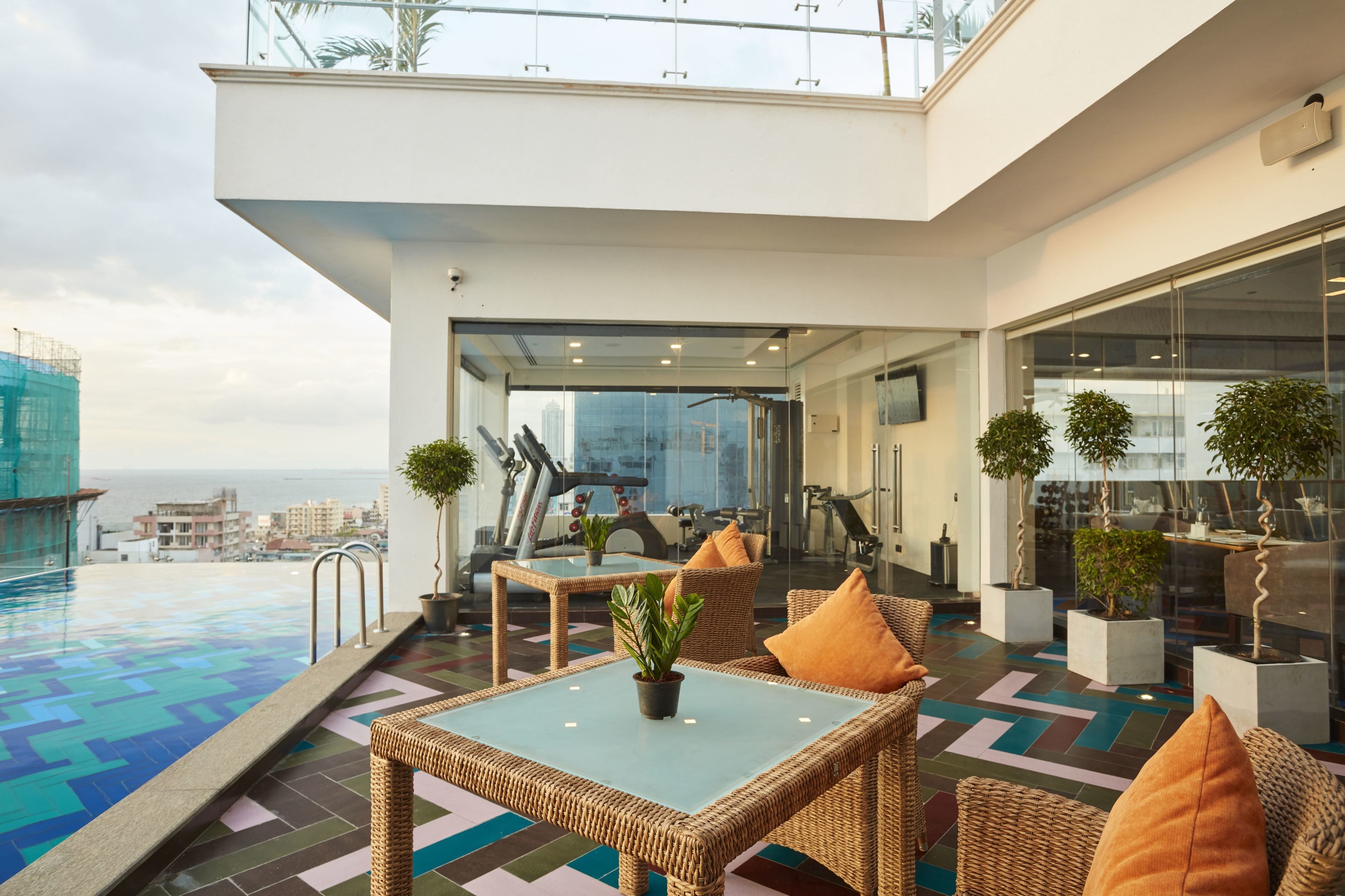 A rooftop terrace with a swimming pool, wicker furniture, and exercise equipment.