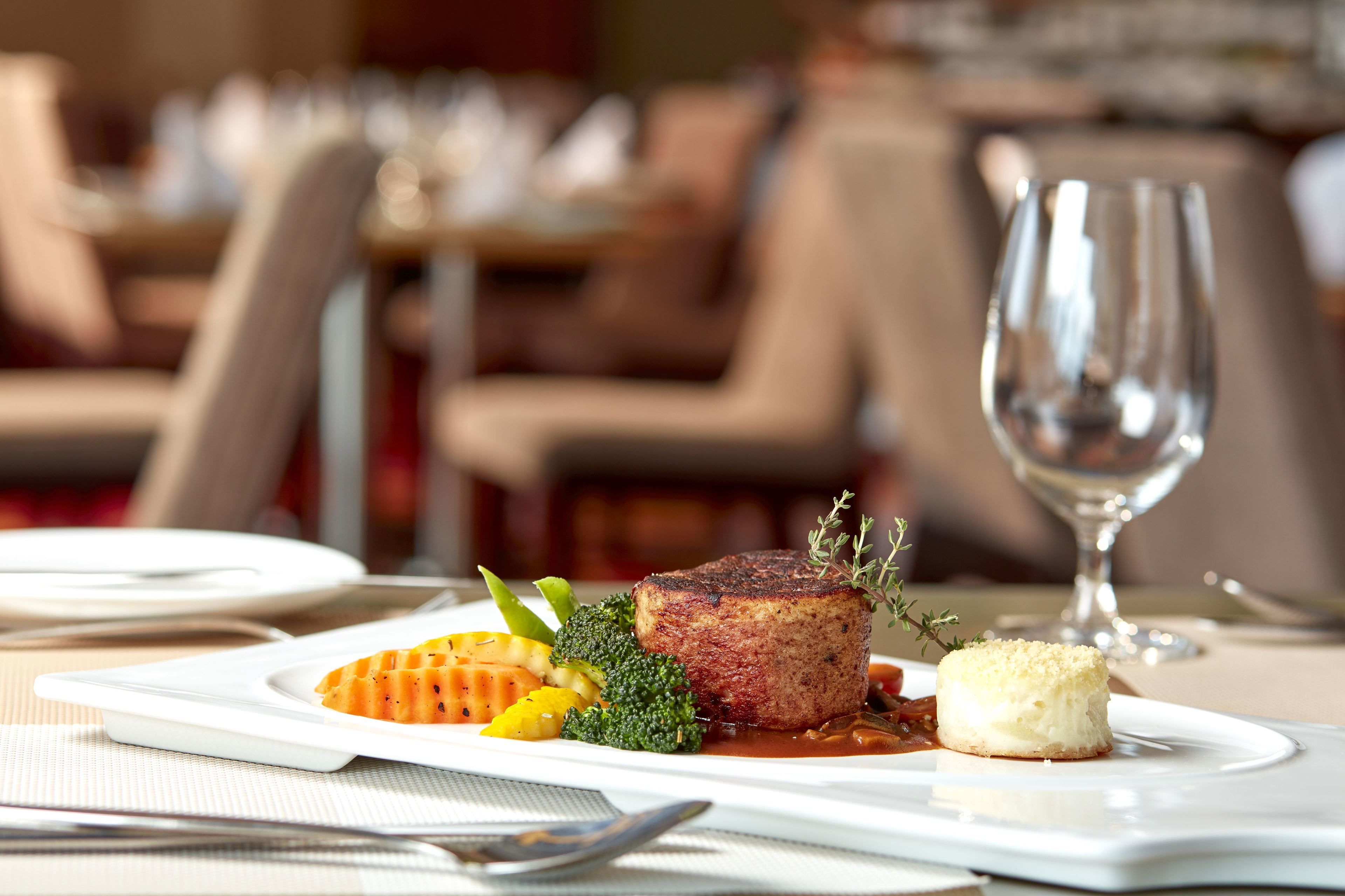 A dining table with a plate of food, a glass of water, and cutlery.