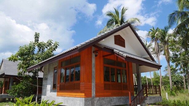 A single-story house with a wooden front and a tiled roof, surrounded by palm trees and greenery. - Nature Home (Ko Pha-ngan)