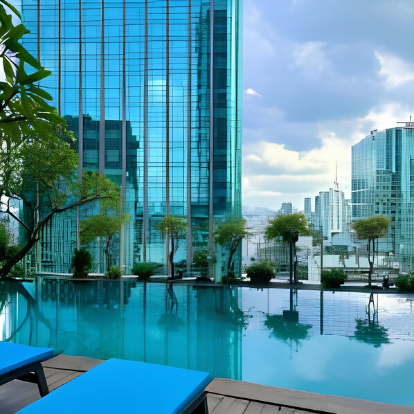 A modern building with a glass facade, a pool area with lounge chairs, and surrounding greenery. - The Myst Dong Khoi (Ho Chi Minh City)