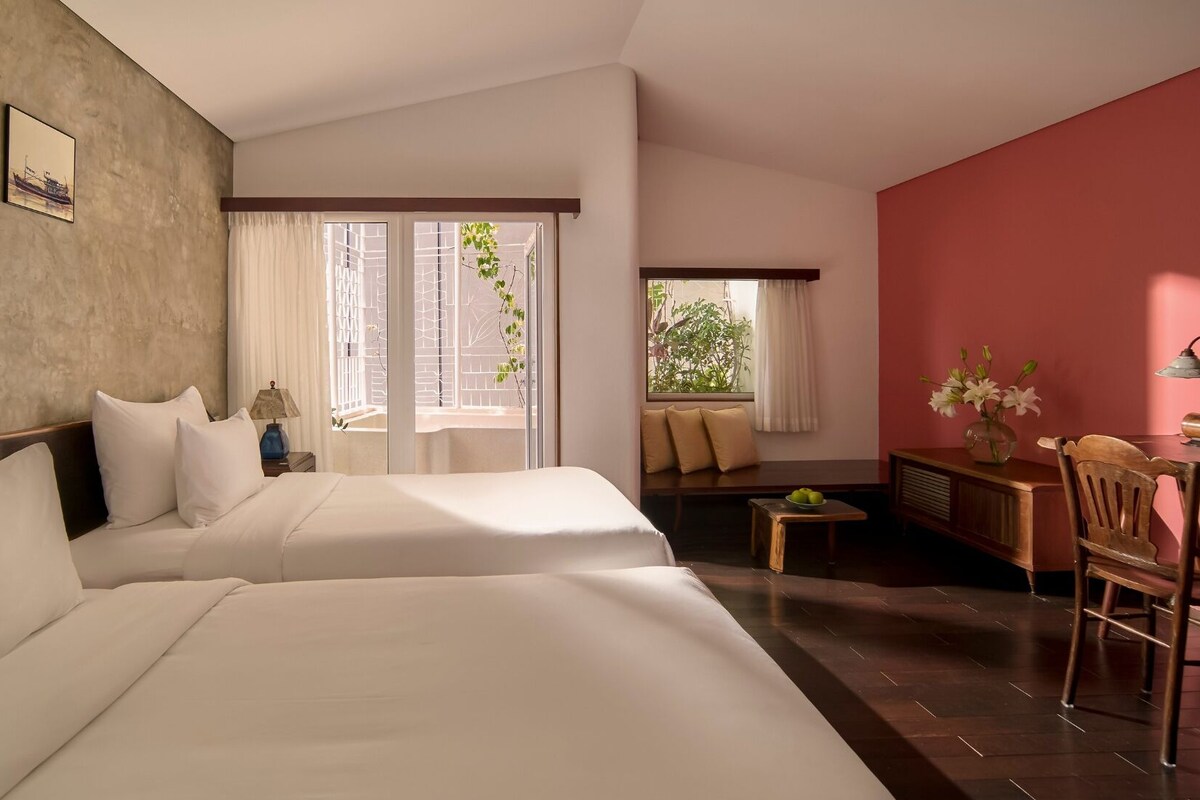 Een hotelkamer met twee bedden, een bureau, een stoel en een klein tafeltje.