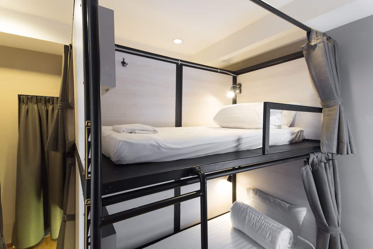 A bunk bed room with a headboard, a bedside table, and a lamp.