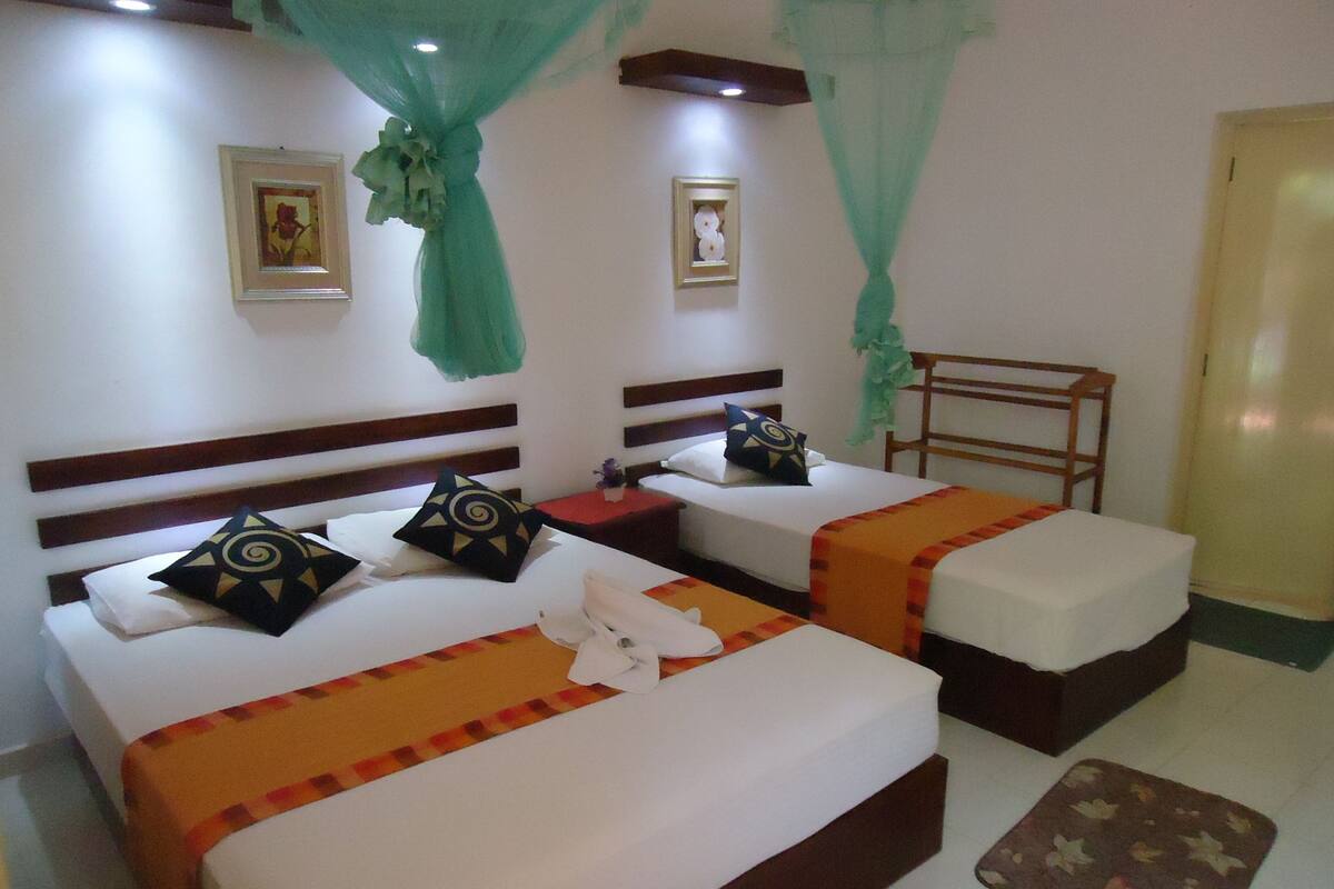 A hotel room with two beds, each with a headboard, a nightstand, and a bedside table.