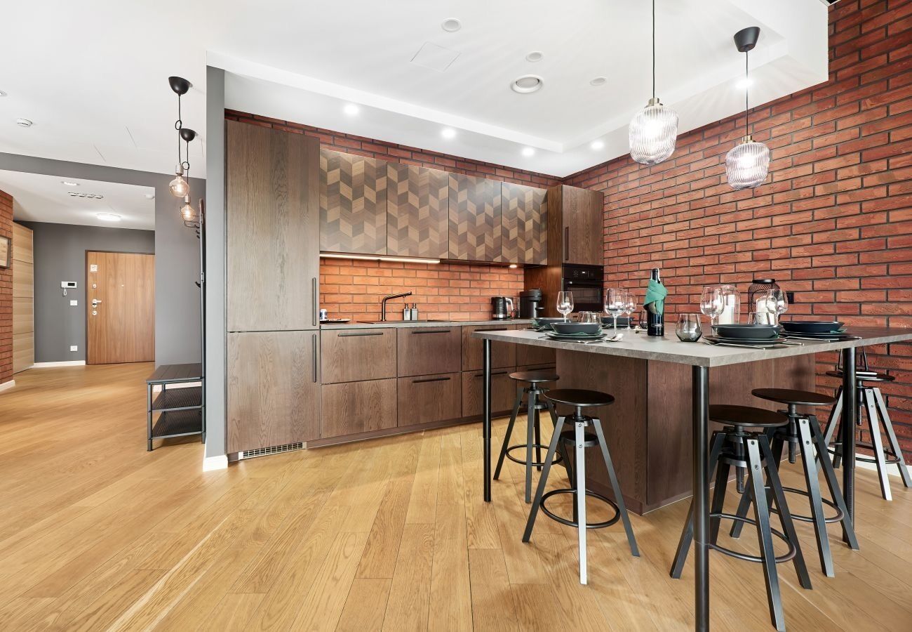 A modern kitchen with a central island, bar stools, and pendant lighting.