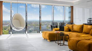 A modern living room with a large window, a hanging chair, a sofa, and a small table.