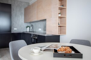 Uma cozinha moderna com armários escuros, bancada de mármore e forno embutido.