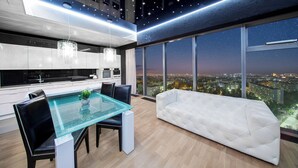 A modern kitchen with a glass dining table and white sofa, large windows with a city view. - Sky Tower Apartments (Wroclaw)