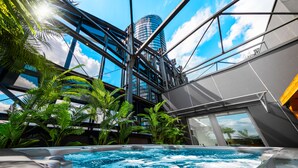 A hot tub with a view of a modern building and palm trees. - Sky Tower Apartments (Wroclaw)