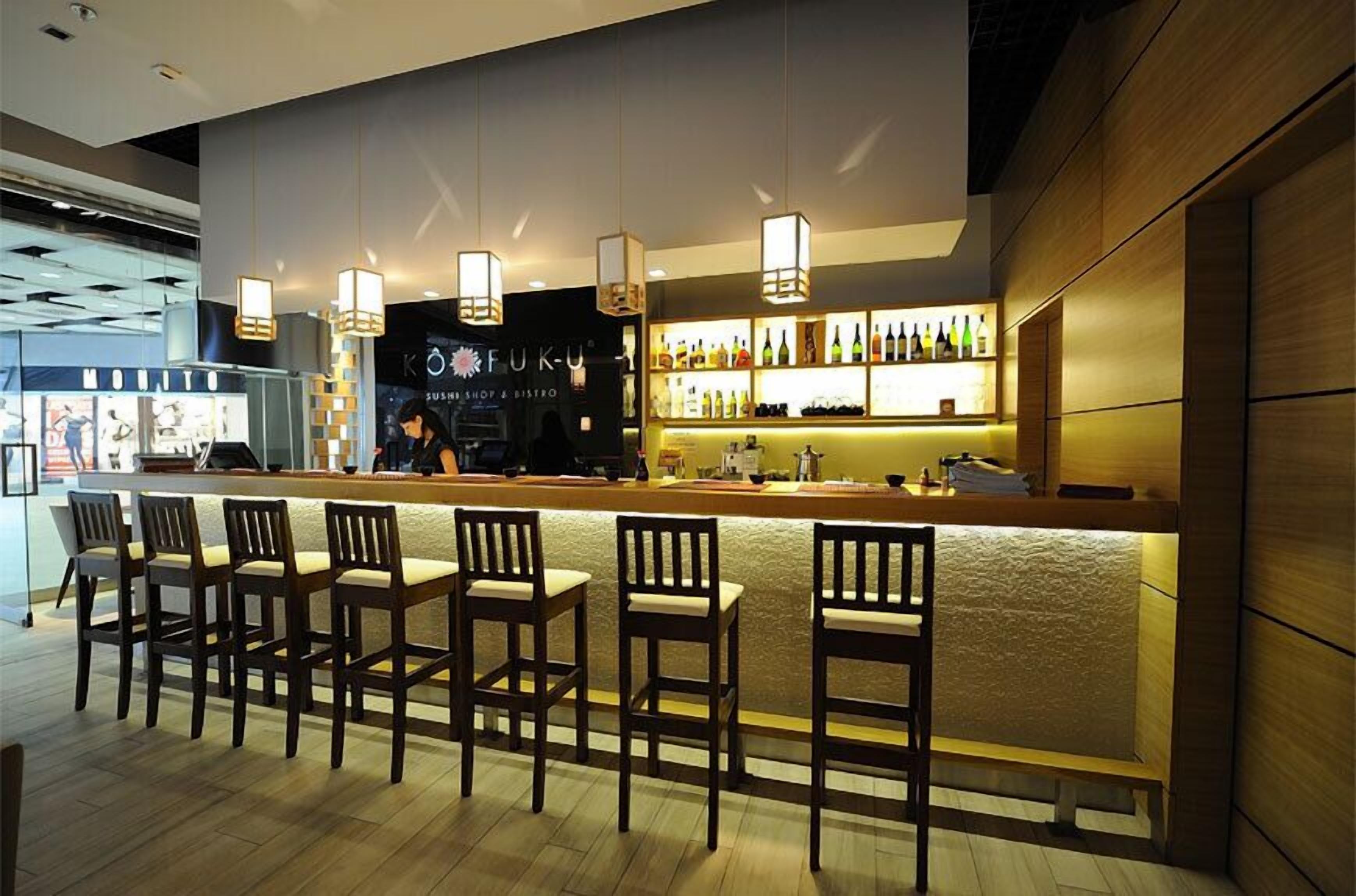 A bar area with a counter, bar stools, and a display of bottles.