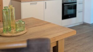 A modern kitchen with white cabinets, a wooden countertop, and a built-in oven. - Arracher Hof (Arrach)