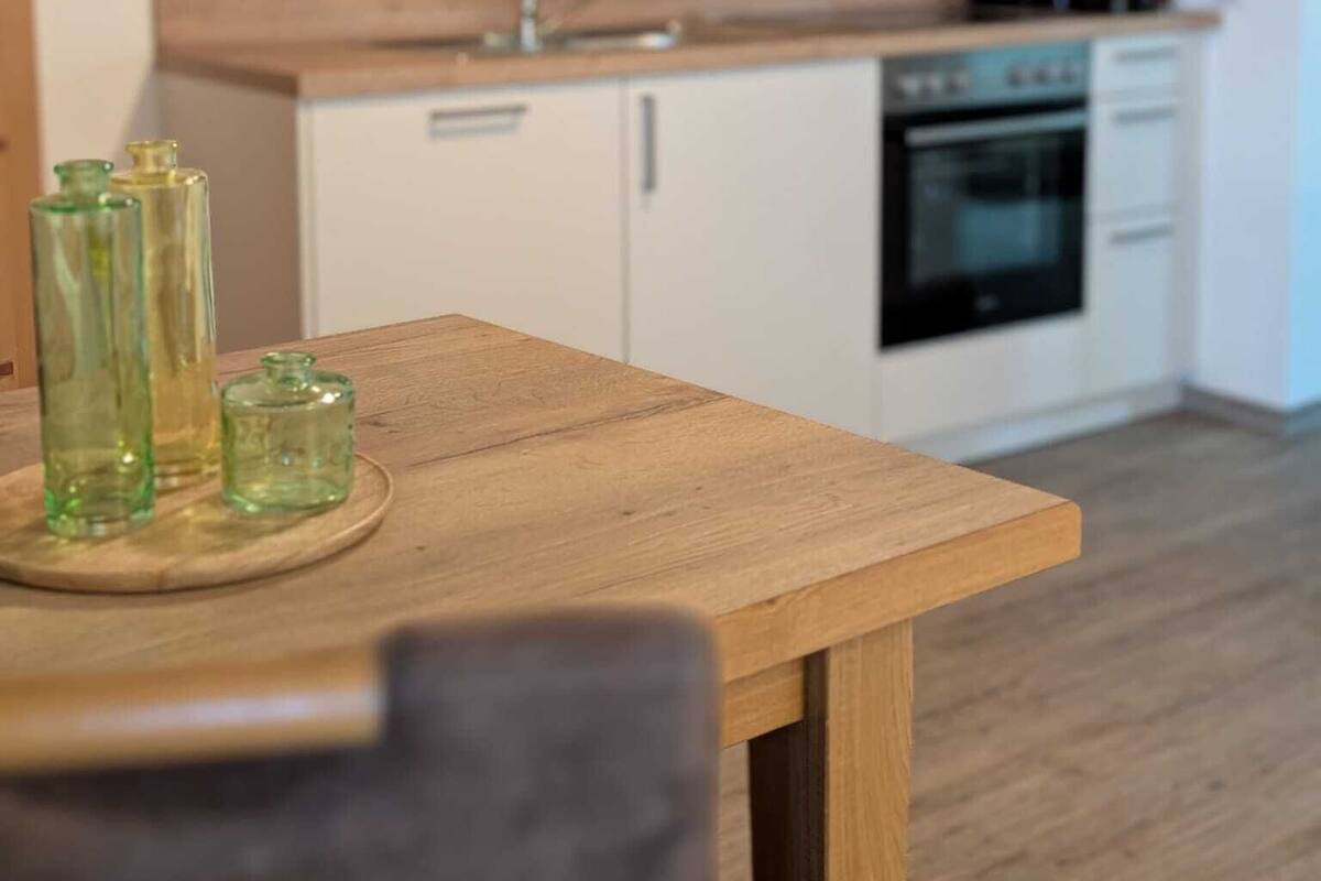 A modern kitchen with white cabinets, a wooden countertop, and a built-in oven.