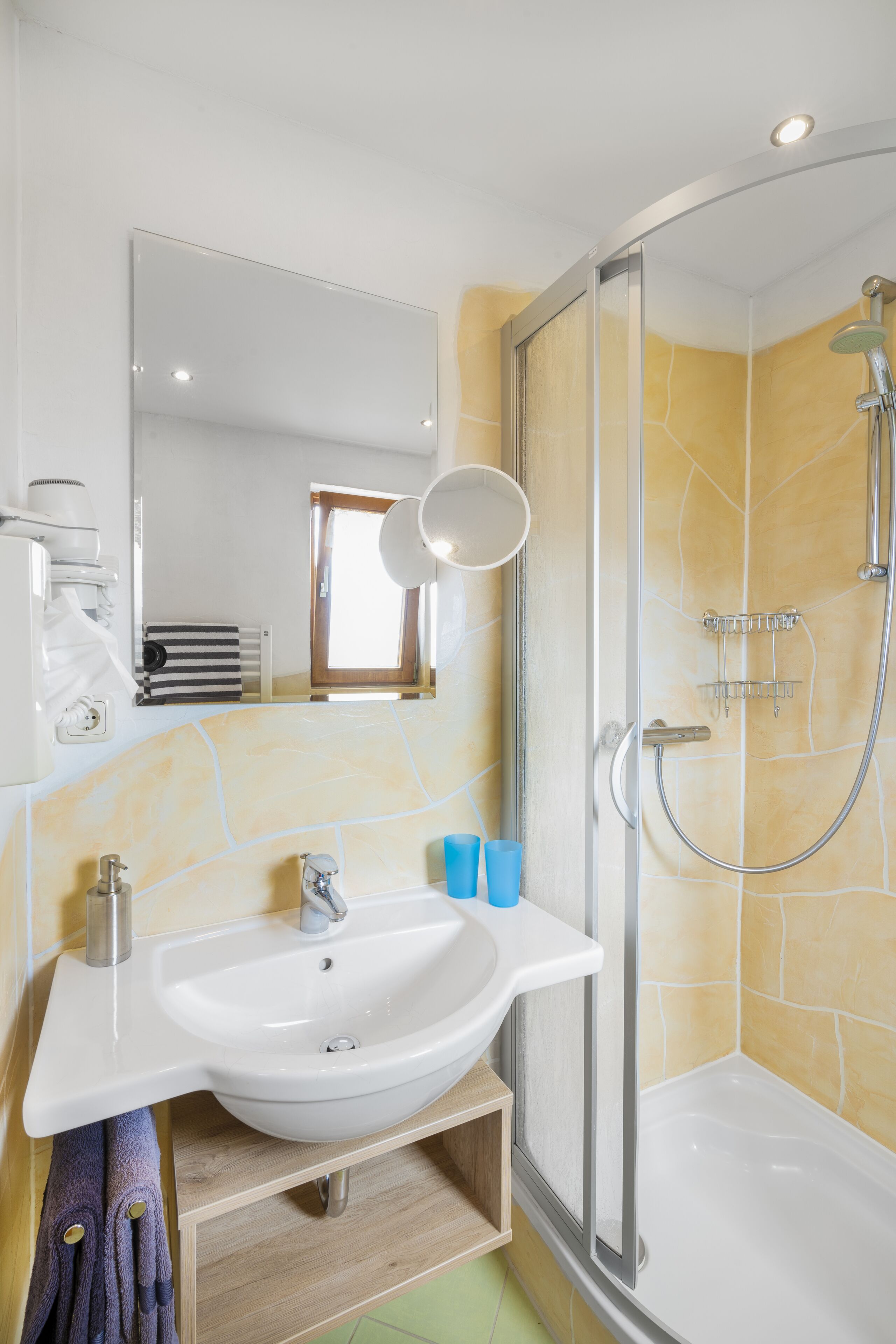A bathroom with a white sink, a glass shower enclosure, and a mirror.