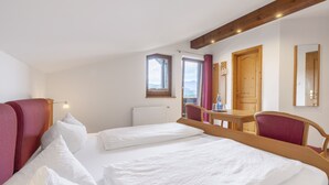 A bedroom with two beds, a wooden ceiling, a window, and a table with chairs. - Arracher Hof (Arrach)
