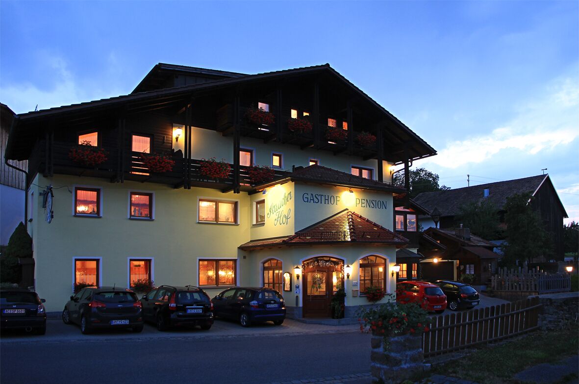 A building with a sign reading "Gasthof Hop" and multiple cars parked in front.