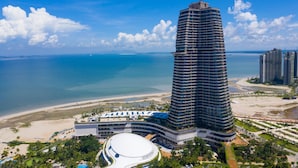 A high-rise hotel with a curved design, beachfront location, and a large central courtyard.