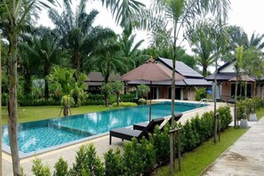Una piscina al aire libre, sillones reclinables de piscina