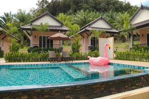 Una piscina al aire libre, sillones reclinables de piscina
