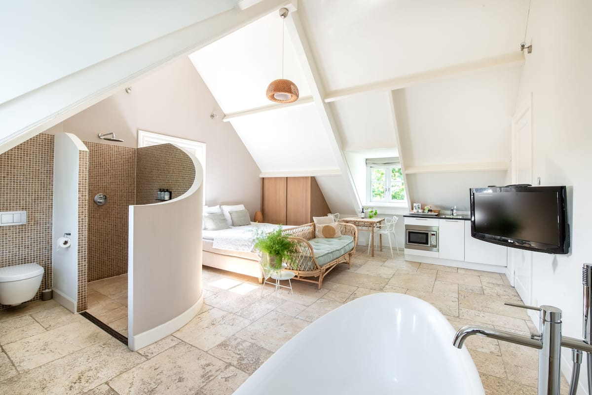 A modern bedroom with a large window, a built-in bed, a bedside table, and a TV mounted on the wall.