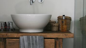 A bathroom with a white sink, wooden vanity, a mirror, and a towel hanging on the vanity.